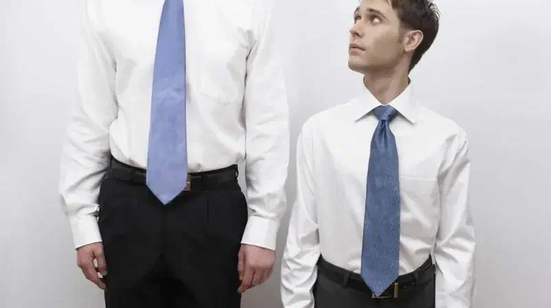 Dos hombres de distinta estatura vestidos con camisa y corbata.