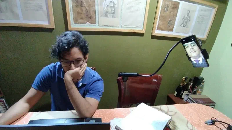 Un estudiante rinde una prueba frente a una computadora y un celular.