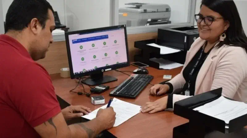 Una servidora pública atiende a un ciudadano en una oficina.