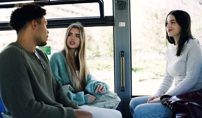 Tres pasajeros sentados dentro de un bus.