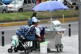 Una persona en moto junto a un vendedor ambulante.