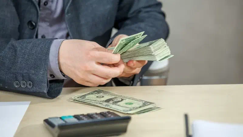 Una persona cuenta billetes junto a una calculadora.